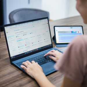 computador sobre a mesa com mãos de uma pessoa aparecendo usando o computador.