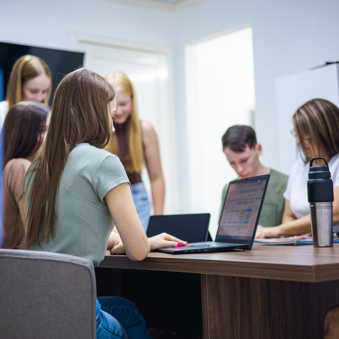 pessoas sentadas em volta de uma mesa trabalhando no computador e conversando.